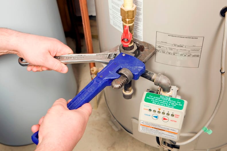 Plumber repairing water heater pipe connection in Homestead, Florida home