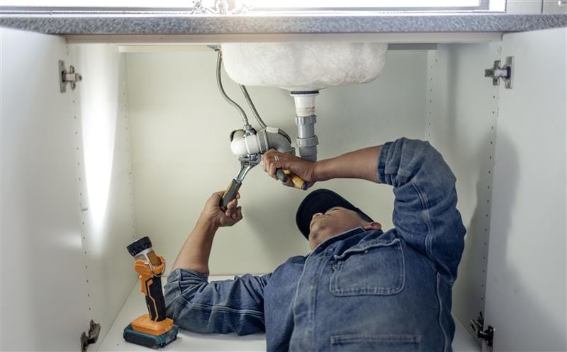 Plumber repairing kitchen sink drain pipes in Homestead, Florida
